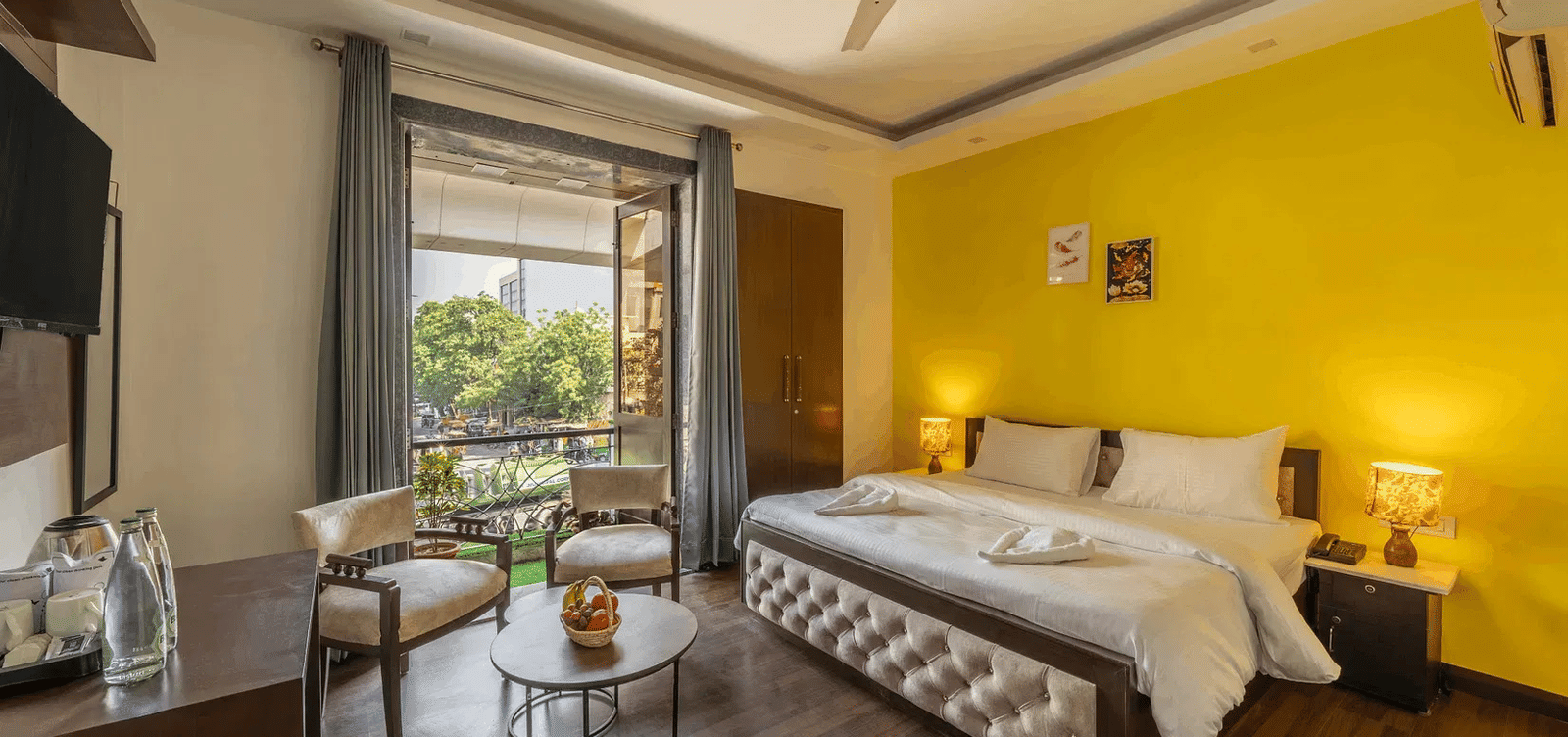 A hotel room with twin beds, yellow accents, and a view of greenery through the window - Lime Boutique Bed & Breakfast | Nehru Place Metro